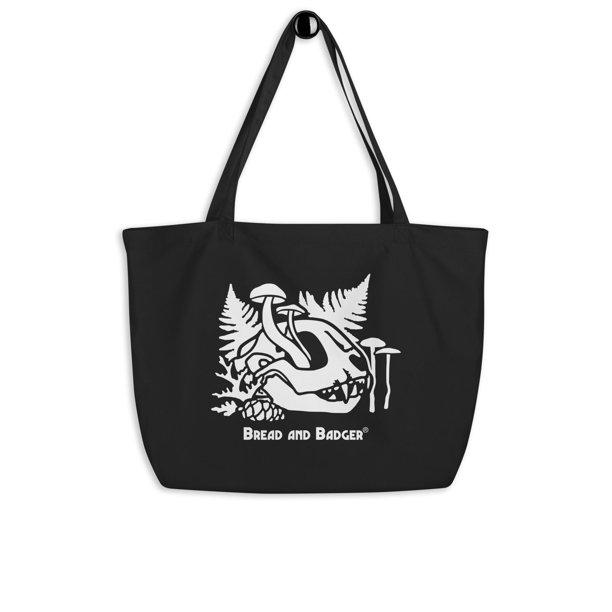 Black tote bag with white cat skull and mushrooms design and 'Bread and Badger' text on a white background