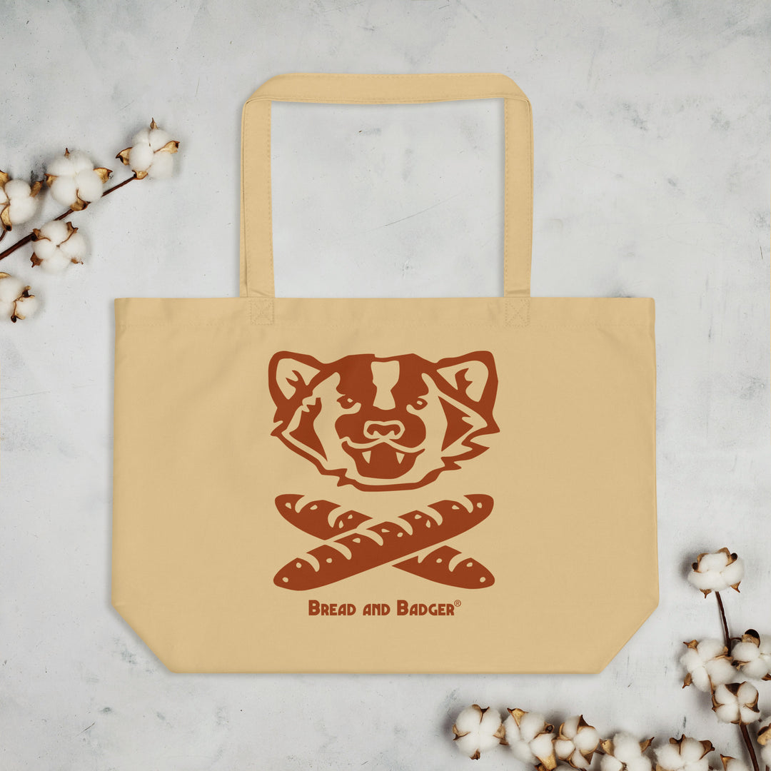 Beige tote bag with a badger design and 'Bread and Badger' text on a light gray background with cotton branches.