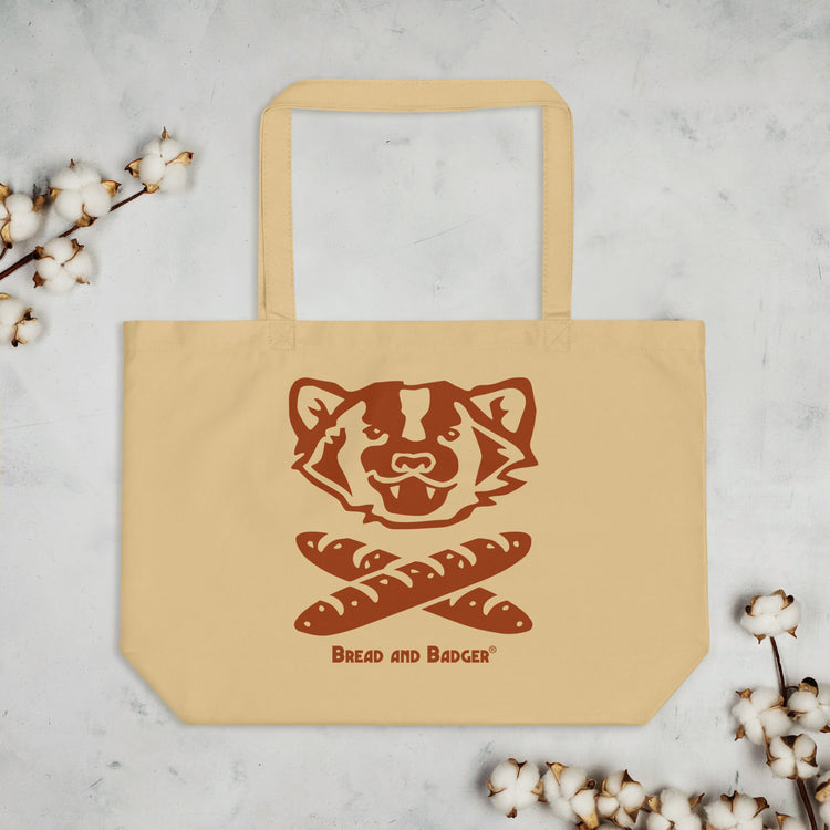 Beige tote bag with a badger design and 'Bread and Badger' text on a light gray background with cotton branches.