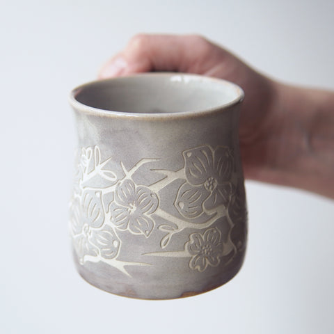dogwood flower engraved onto a handmade mug, held by the handle