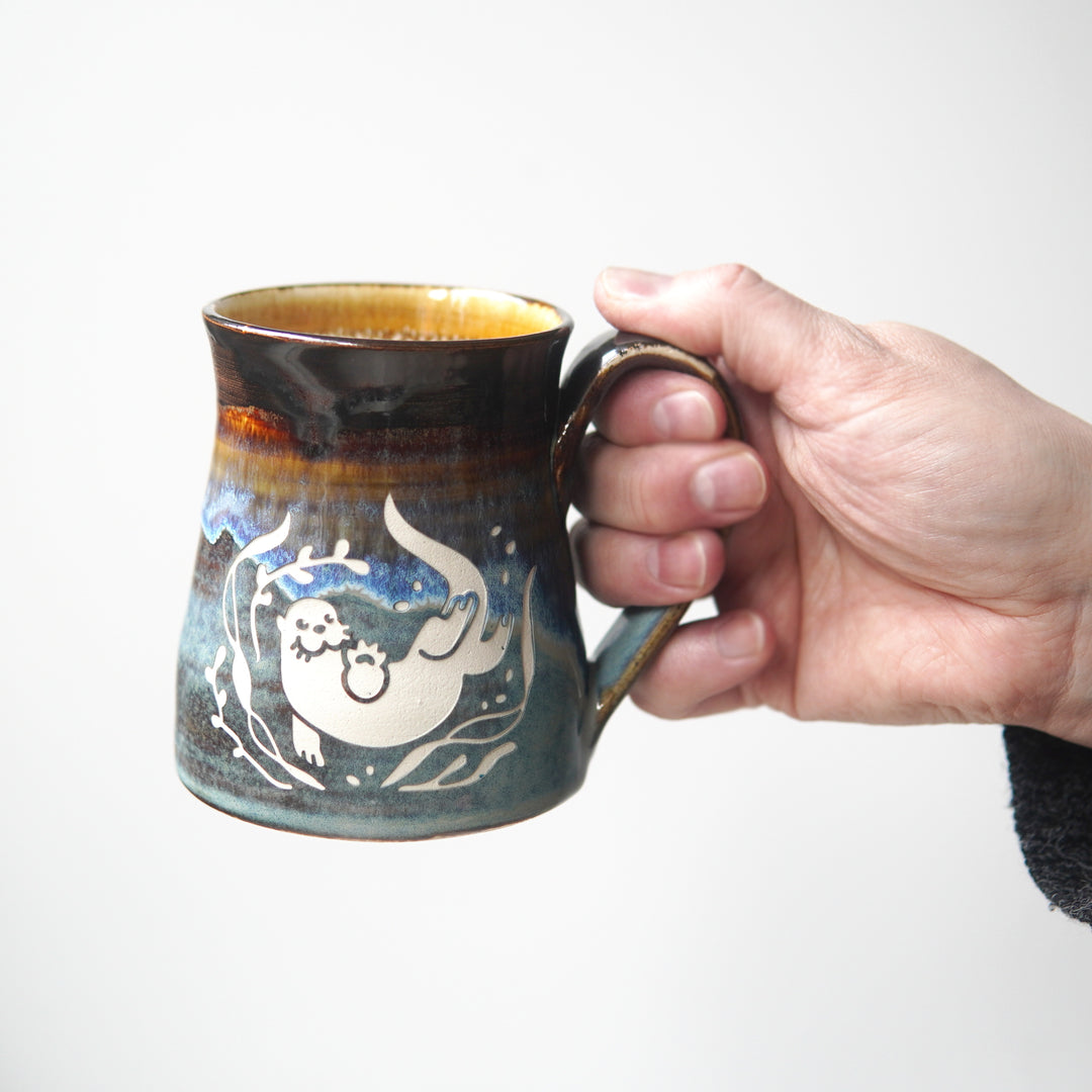 Otter mug held by a hand