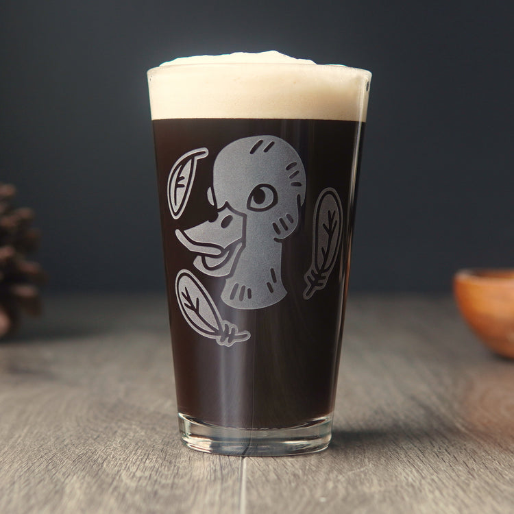 pint glass etched with a duck head, surrounded by three feathers, full of dark beer.