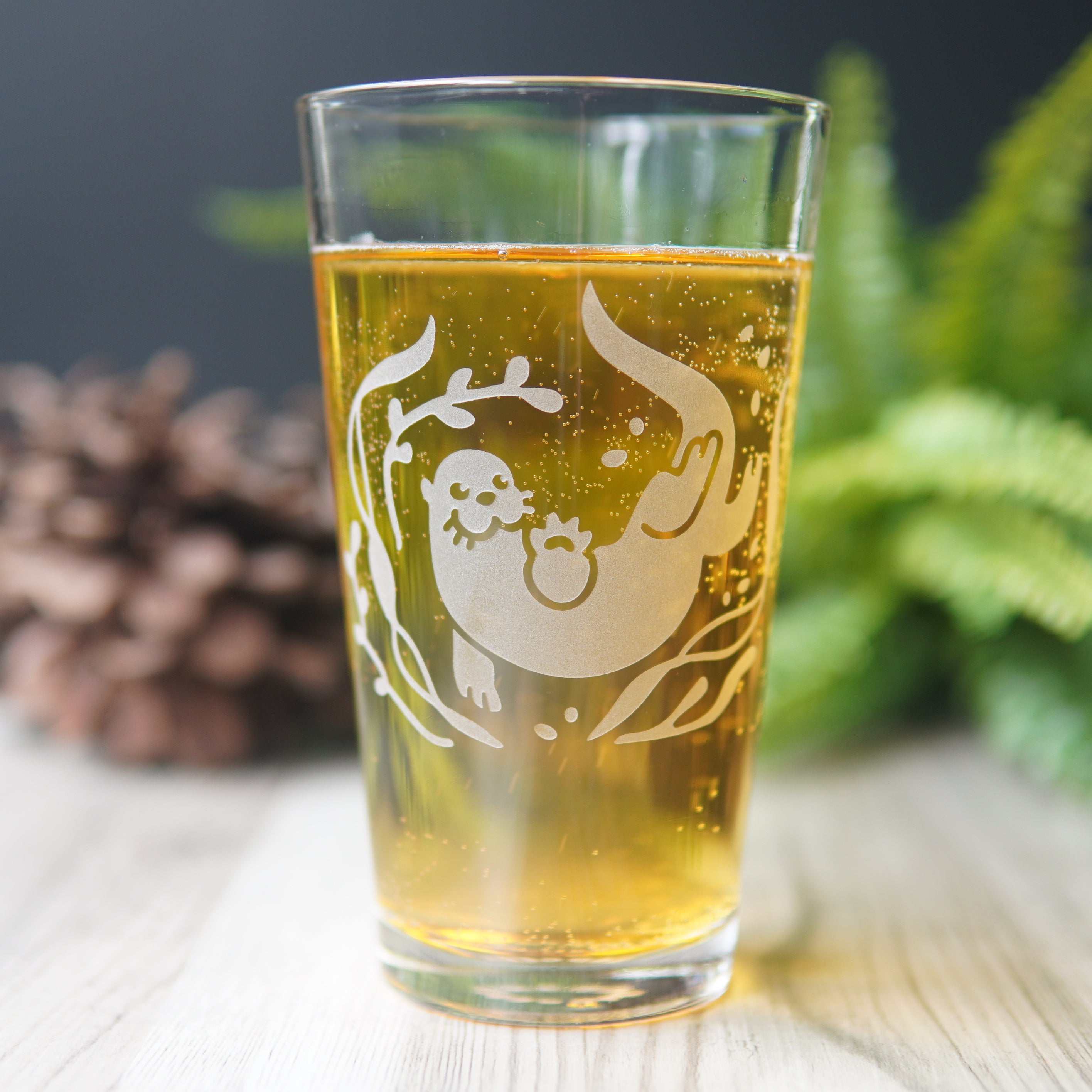 Otter and kelp engraved on a pint glass full of beer