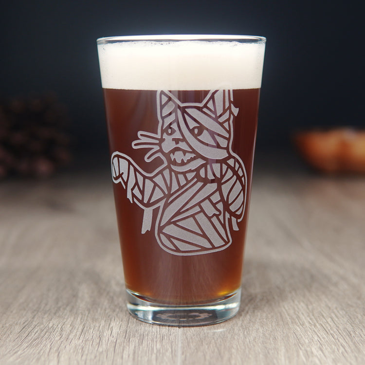 pint glass etched with the upper body of a mummy cat. The cat's mouth is open, arms slightly outstretched, and wrappings are coming loose.