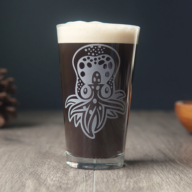 pint glass etched with a cute baby octopus. It has dots across its head and a few tentacles. The glass is full of dark beer.