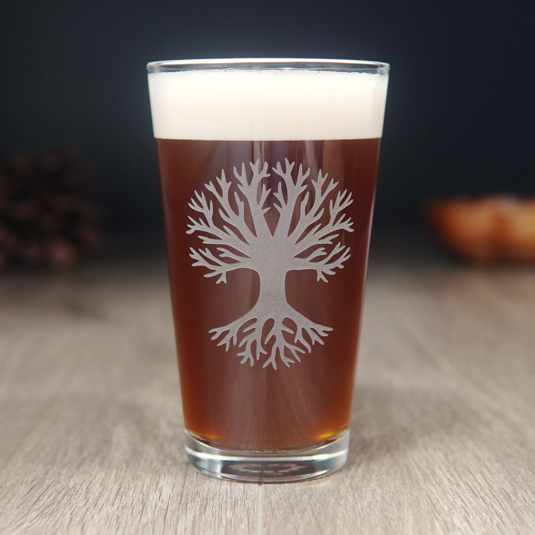 pint glass etched with a large bare tree, full of red beer or kombucha