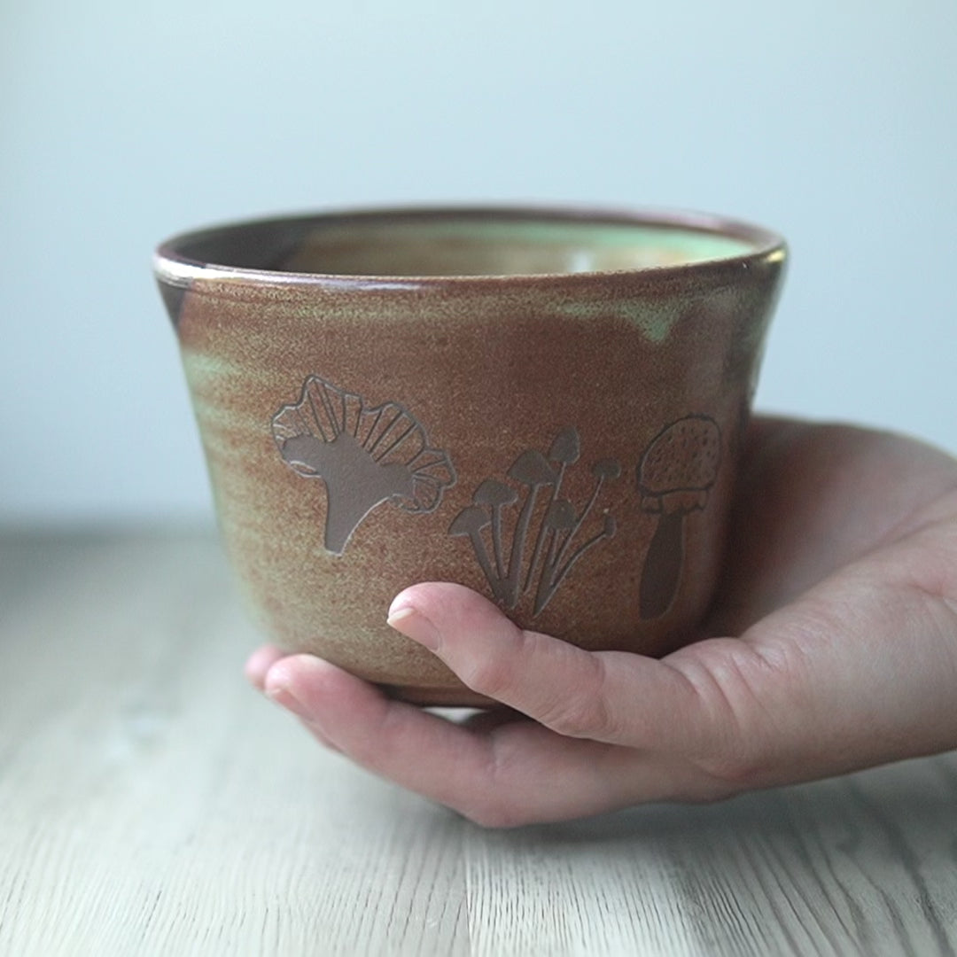 green and rust "copper" color medium pottery bowl engraved with mushrooms