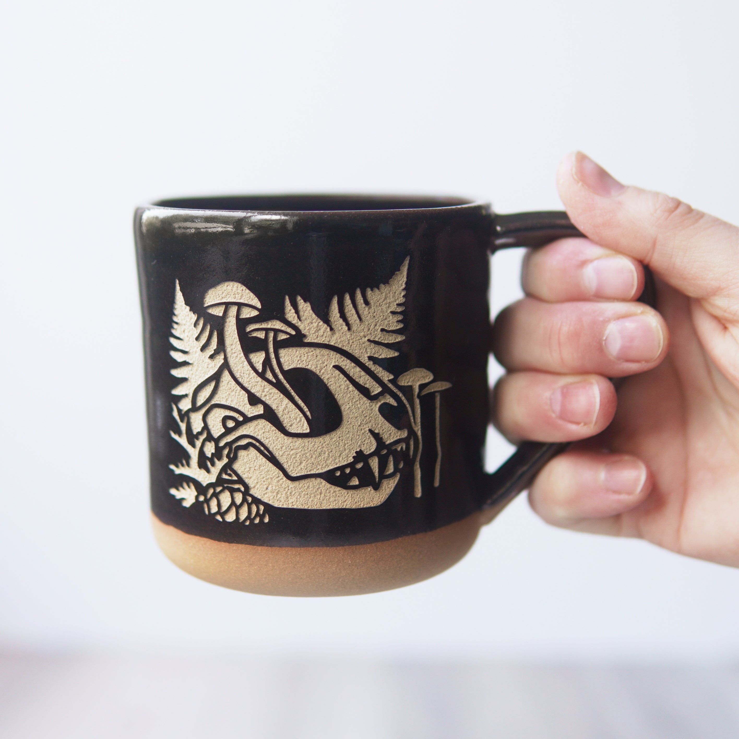 decaying cat skull and mushrooms mug, held by its handle