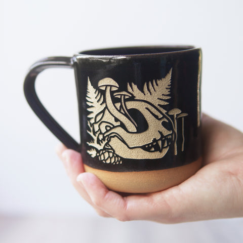 decaying cat skull mug, held in the palm of a hand