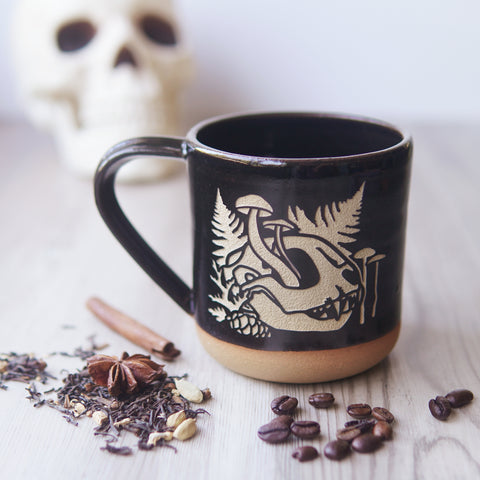 black mug engraved with a cat skull and mushrooms