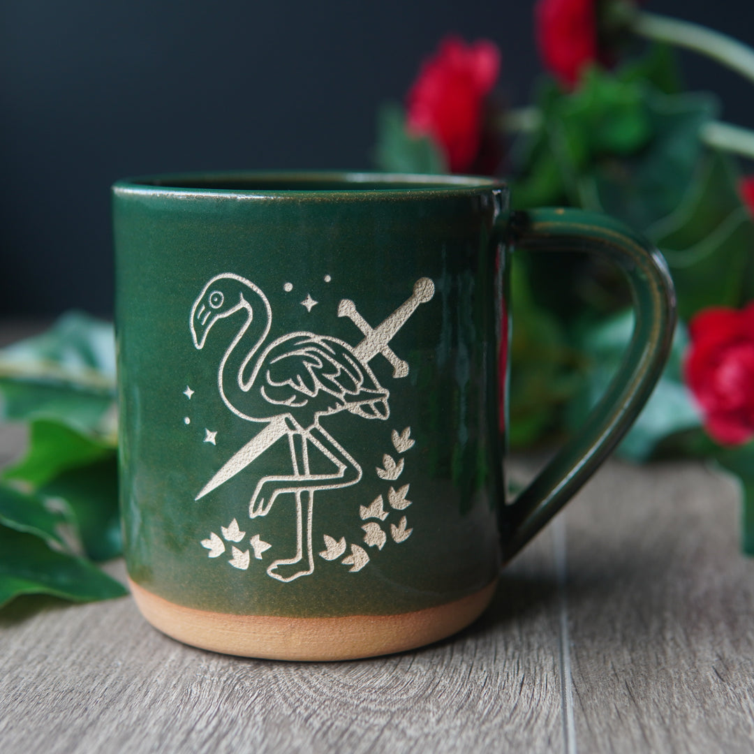 pine green mug engraved with a flamingo with a sword through it