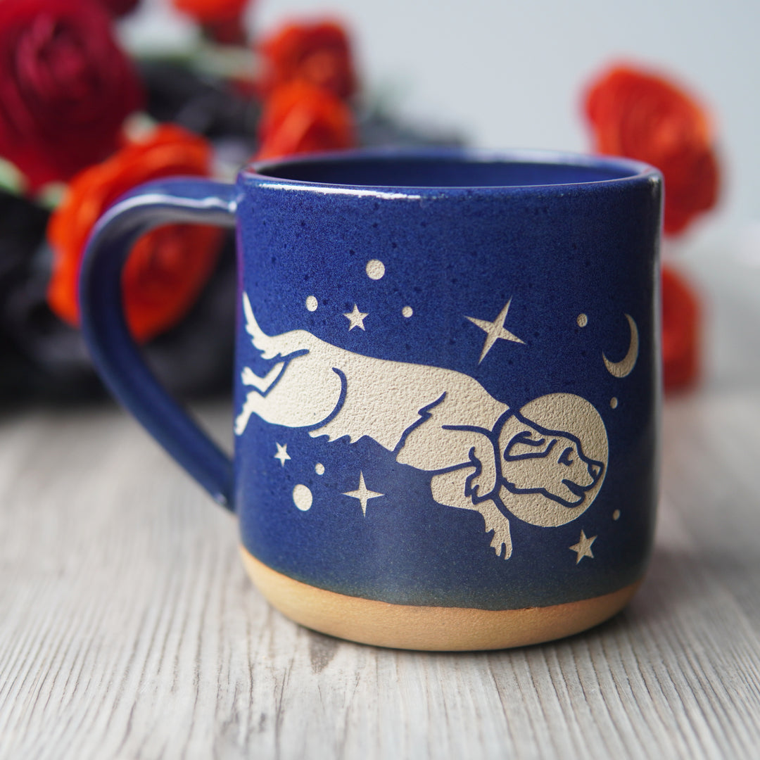 cobalt blue space dog mug, with flowers in the background