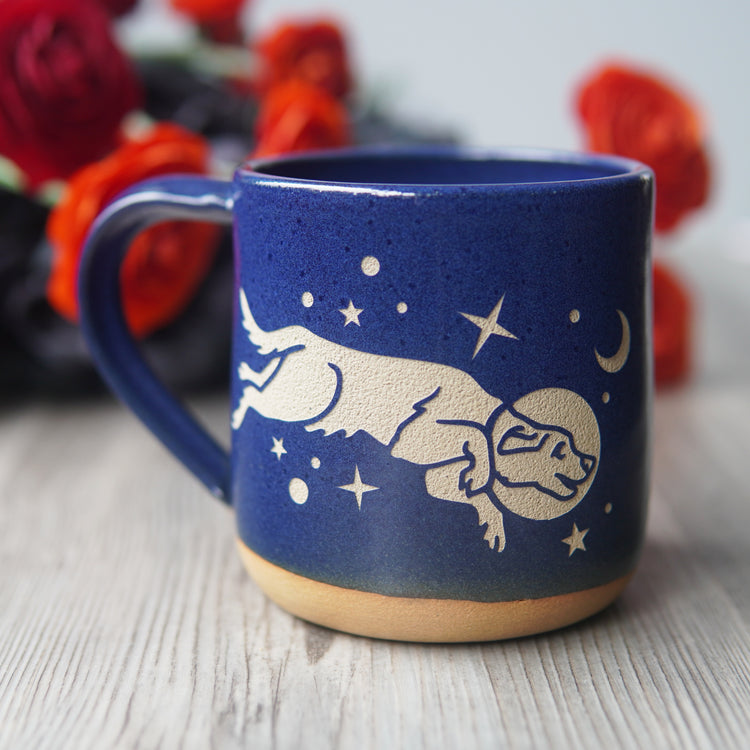 cobalt blue space dog mug, with flowers in the background