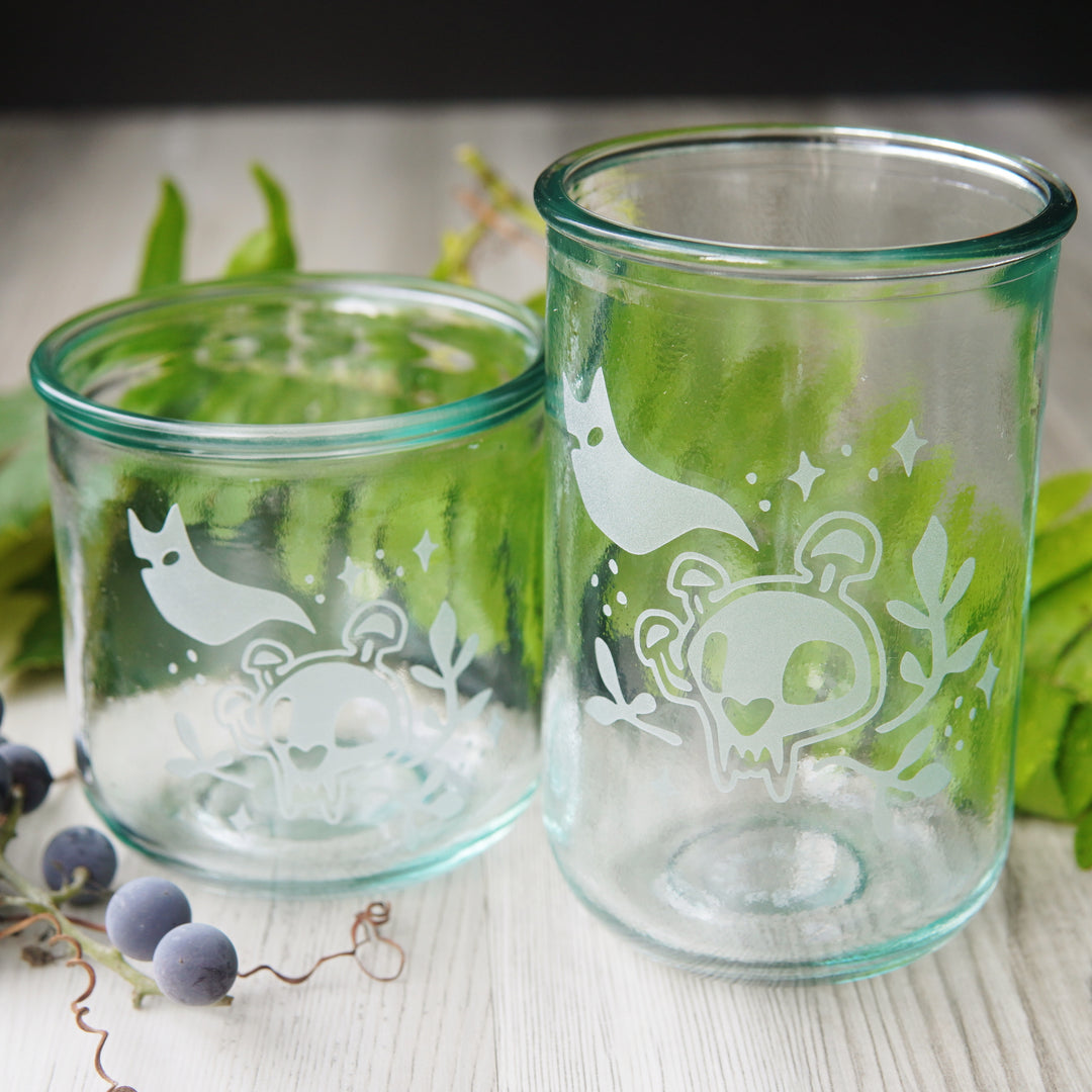 short and tall haunted cat skull glasses in front of fern fronds and grapes