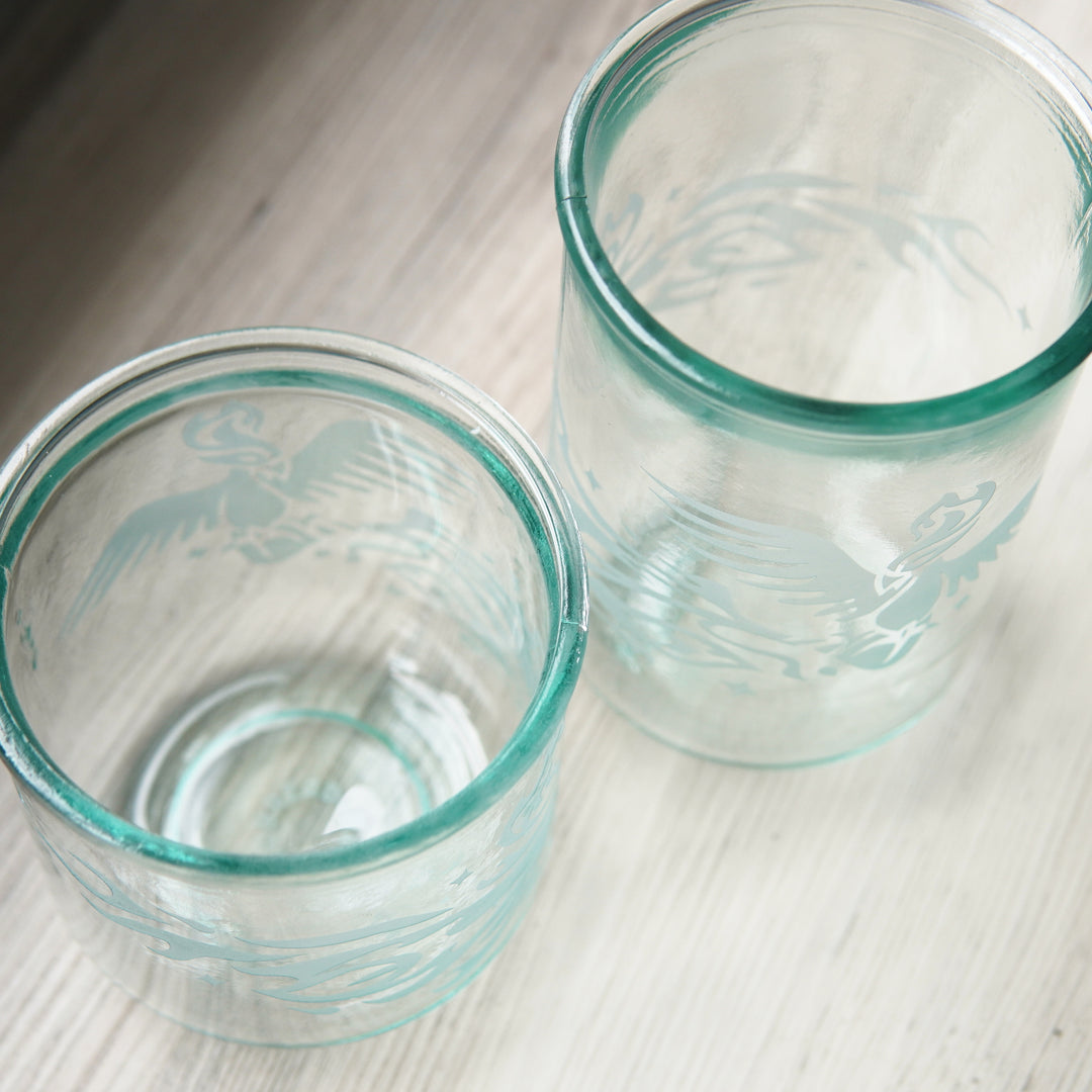 Phoenix birds engraved onto blue-green tinged glassware, seen from above