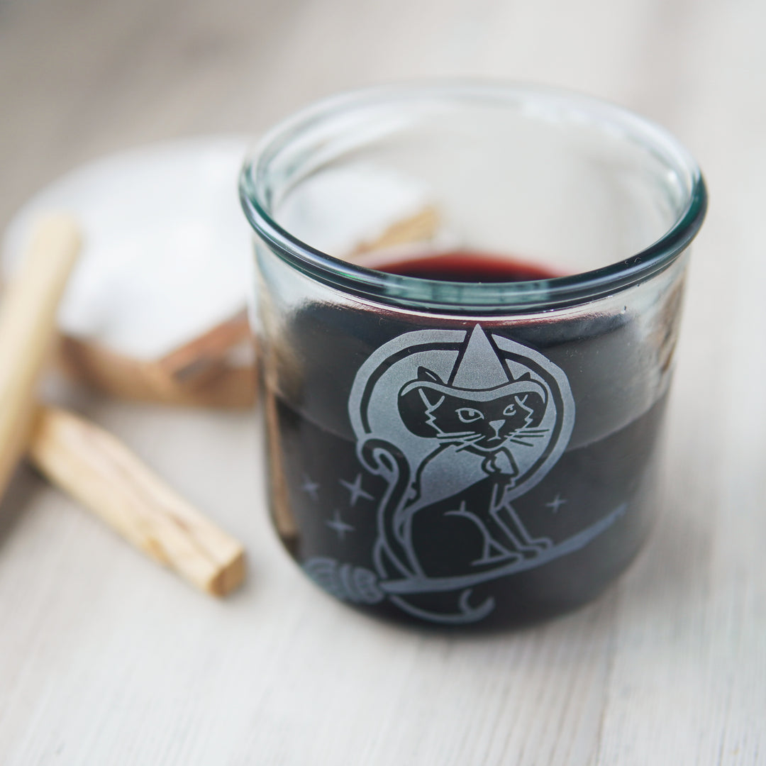 witch cat engraved onto a short glass of red wine