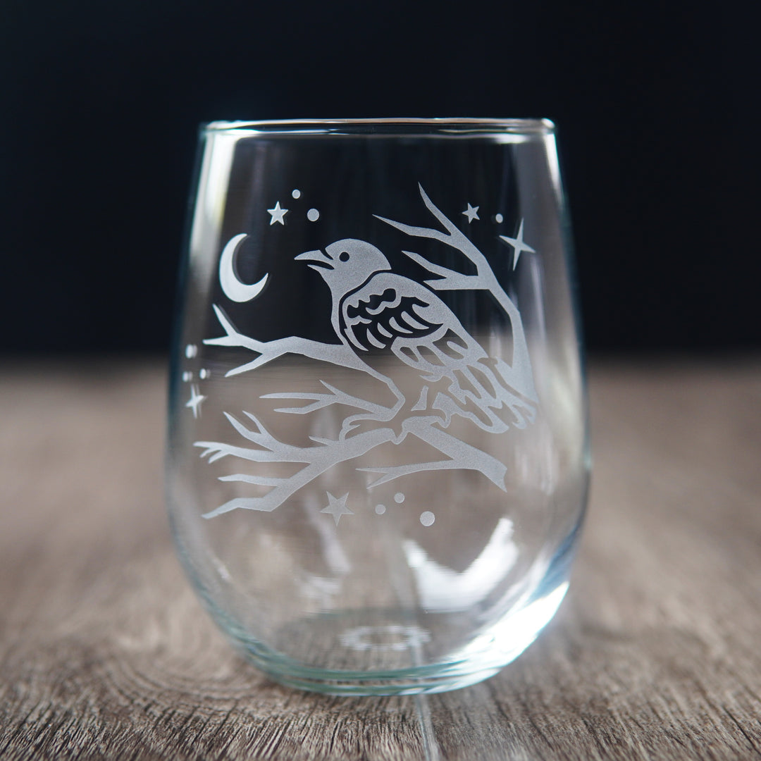 stemless wine glass etched with a crow in a tree, facing a crescent moon and stars