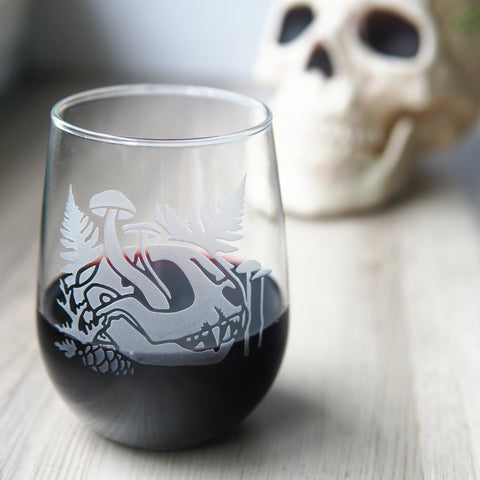 stemless wine glass etched with a cat skull, mushrooms, and ferns