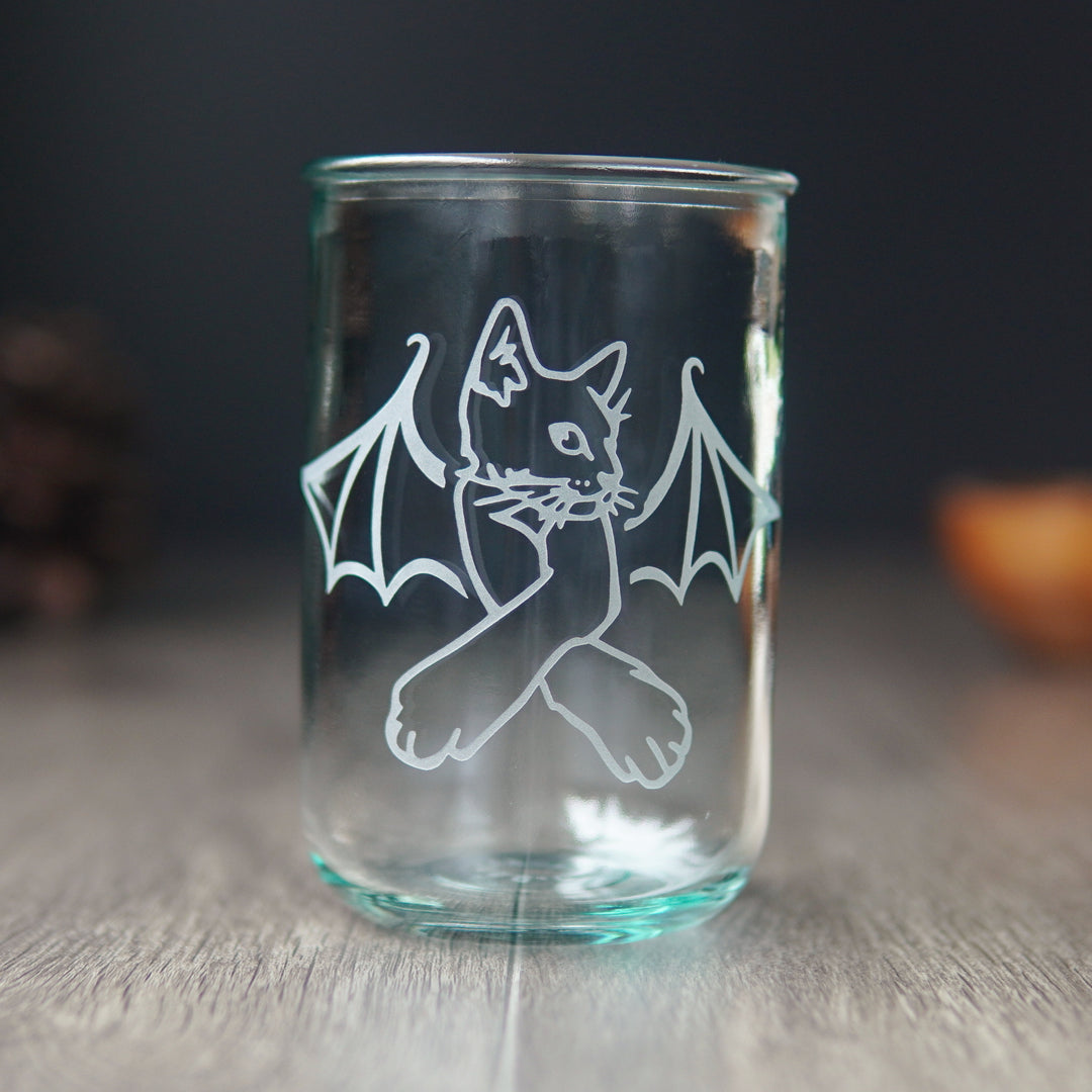 cat with bat wings engraved on a tall blue-tinged glass tumbler