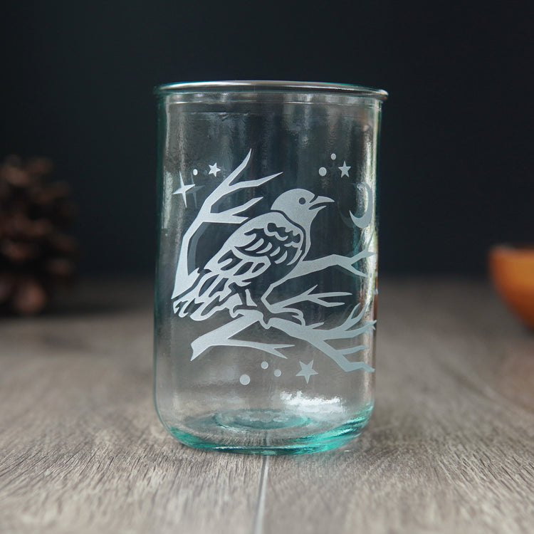 blue-tinged tall glass etched with a crow in a tree at night