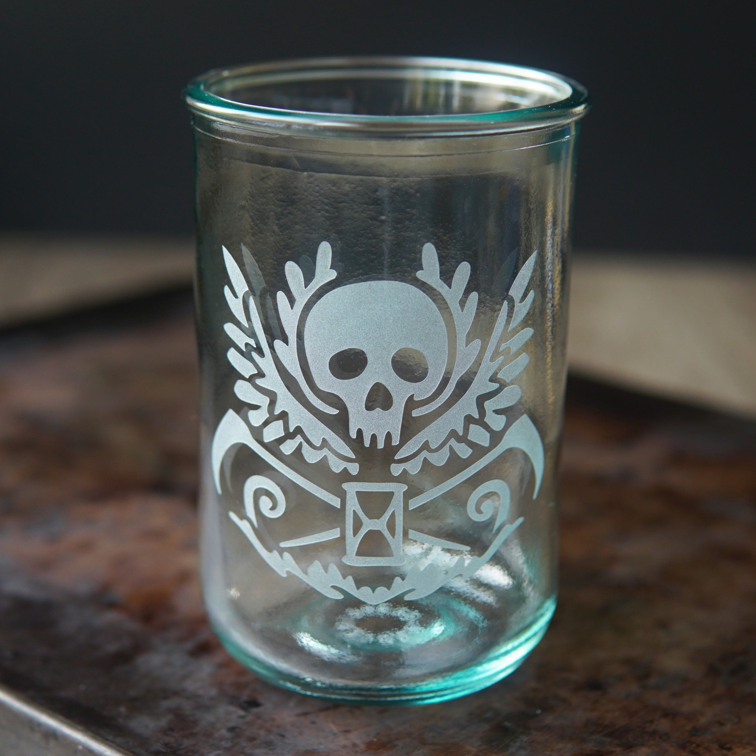 winged skull, scythes, and hourglass etched onto a straight-sided glass