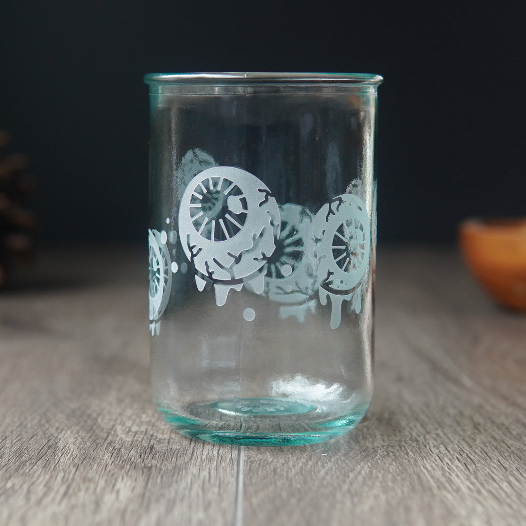 dripping eyeballs etched onto a tall  green-tinged glass cup