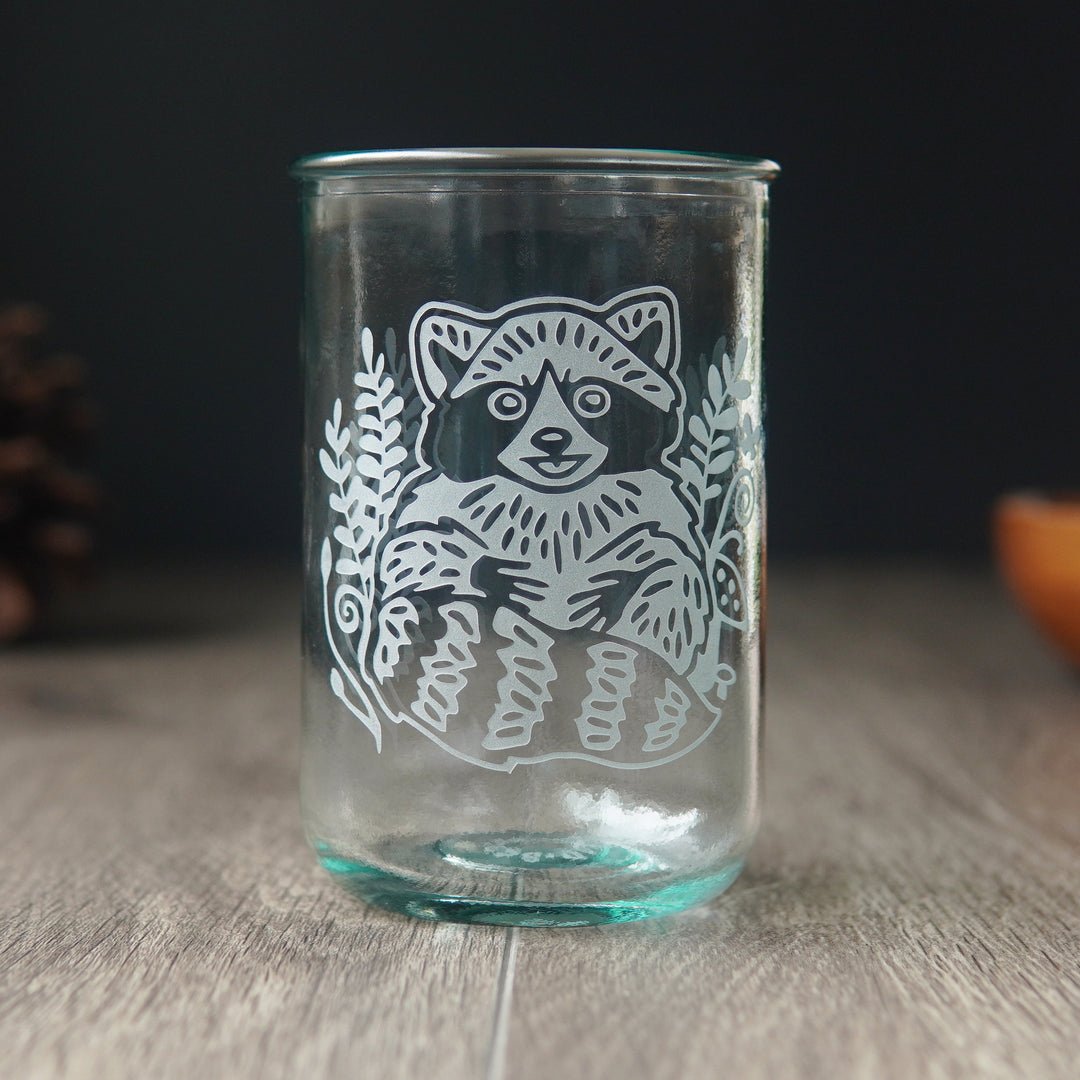 cute raccoon engraved on a bluegreen-tinged tall glass