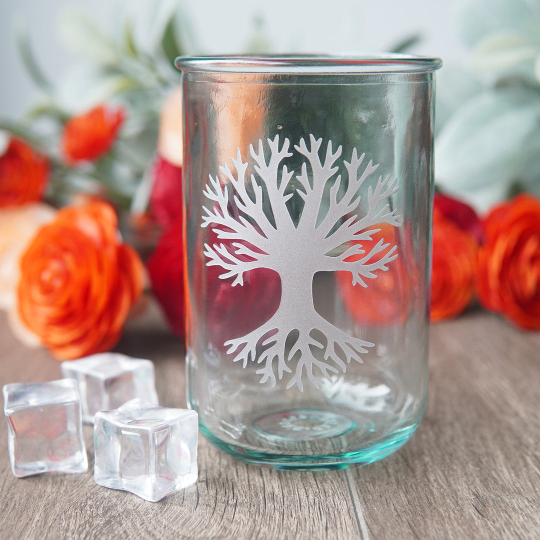 Tree engraved on a tall glass with ice cubes and orange flowers