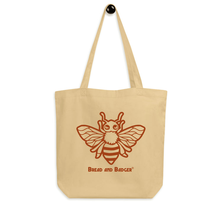 Beige tote bag with a red bee illustration and 'Bread and Badger' text on a white background