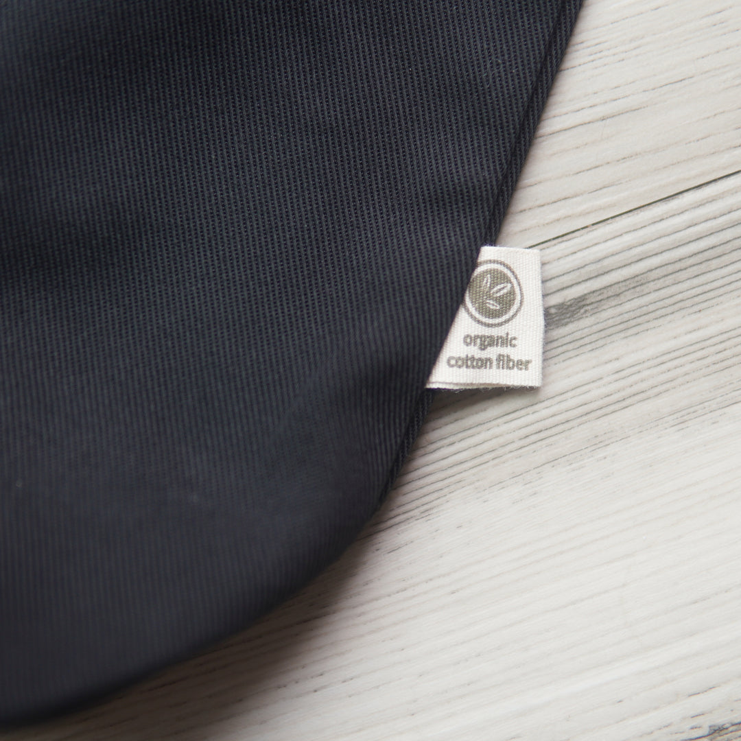 small tag printed with a leaf design and the text, "organic cotton fiber" on the outside edge of a black tote bag