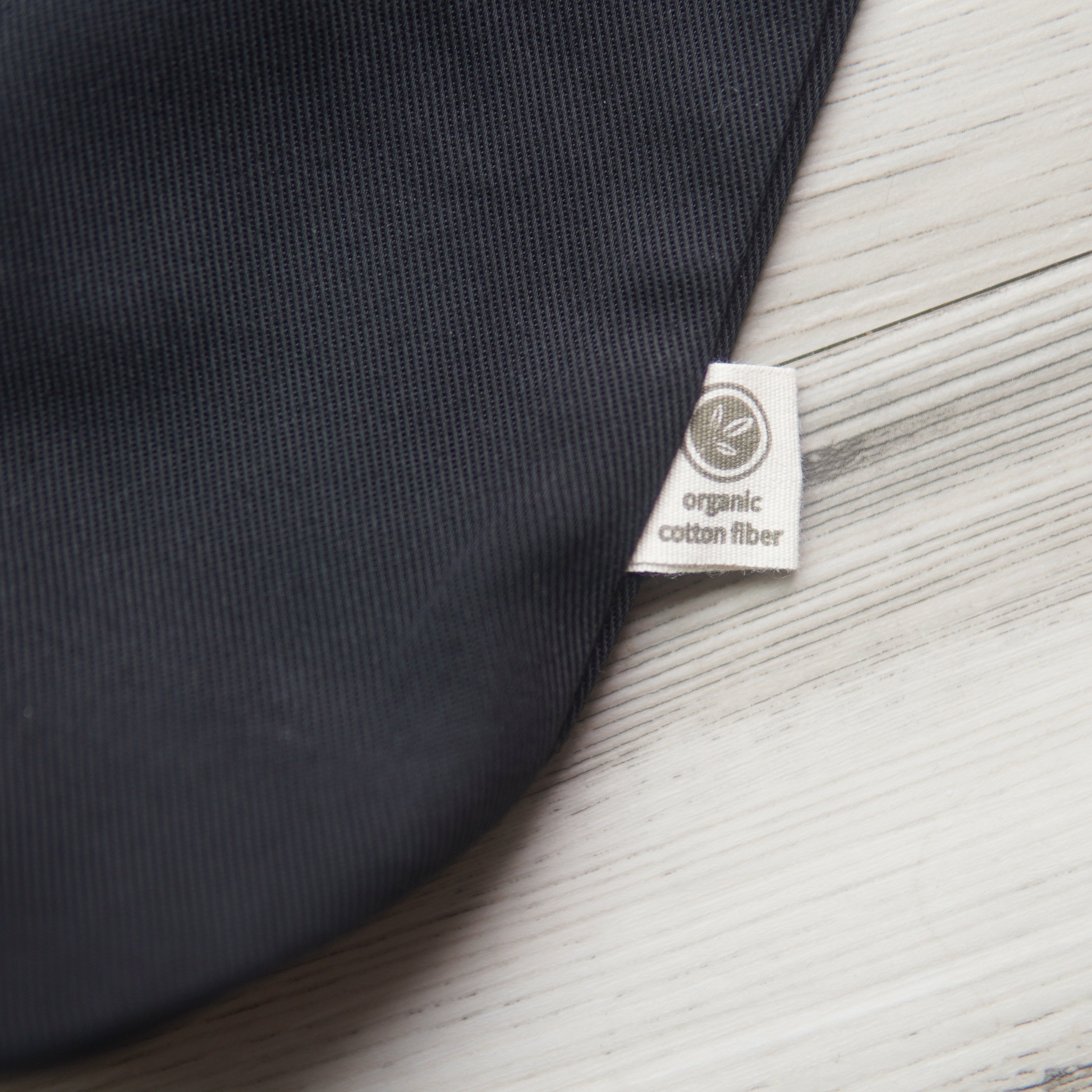 small tag printed with a leaf design and the text, "organic cotton fiber" on the outside edge of a black tote bag