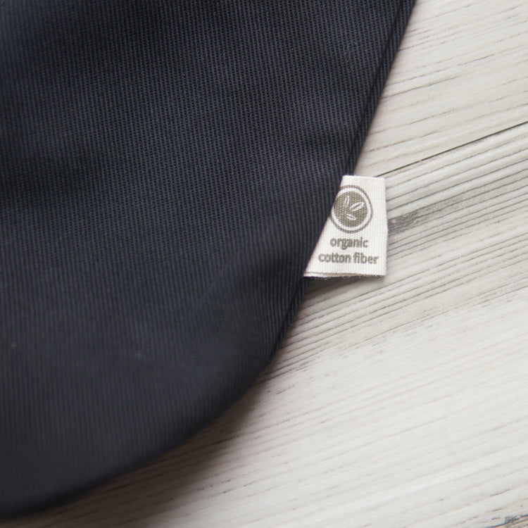 small tag printed with a leaf design and the text, "organic cotton fiber" on the outside edge of a black tote bag