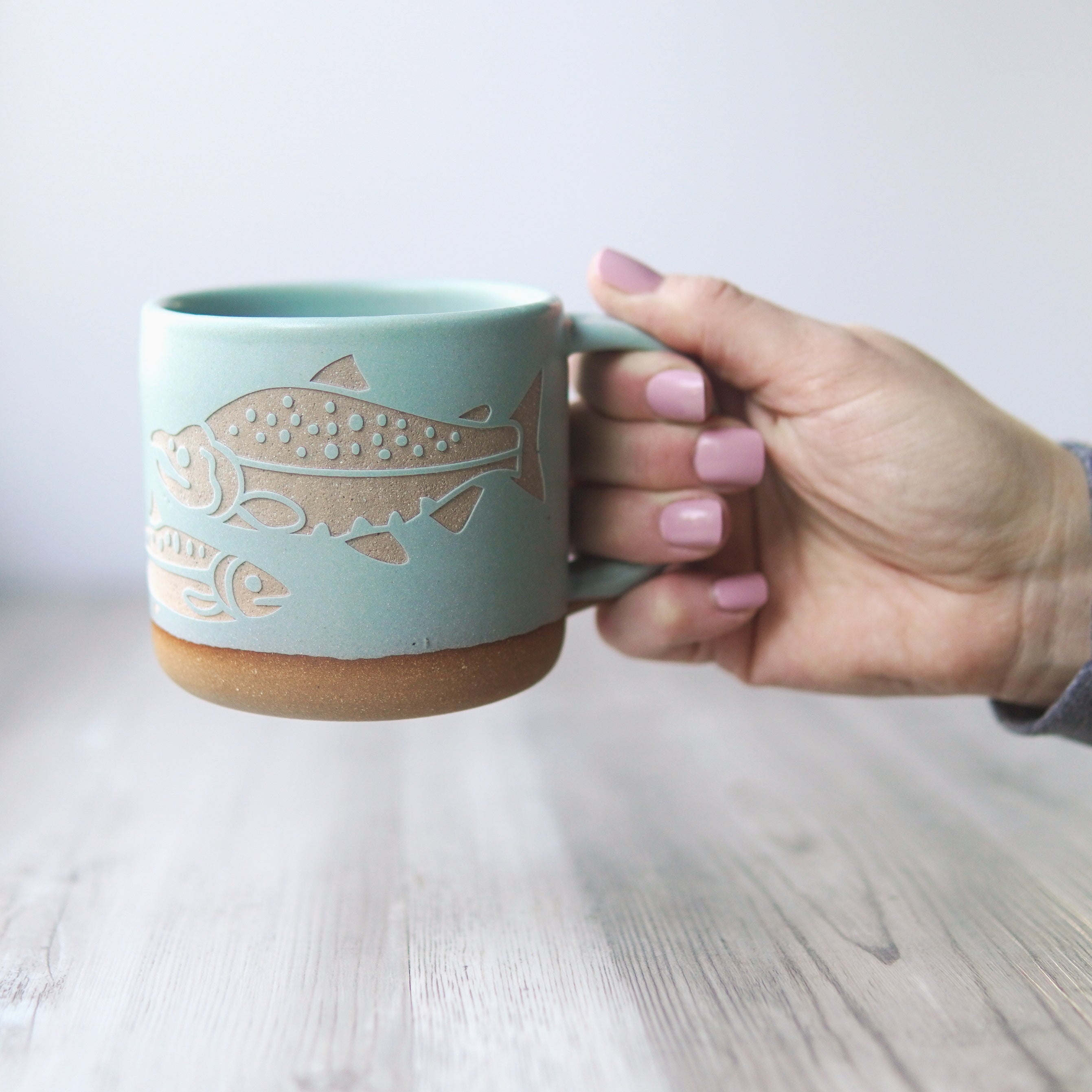 Salmon Fish Mug in Rain (blue-grey), held by a hand