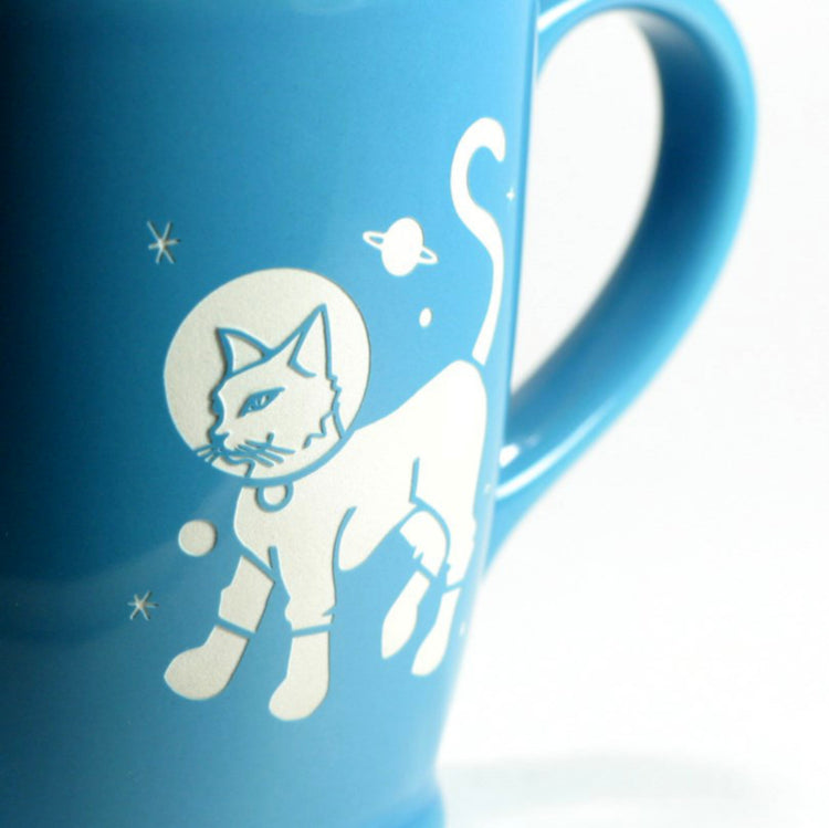 close up of engraving on sky blue astronaut cat mug