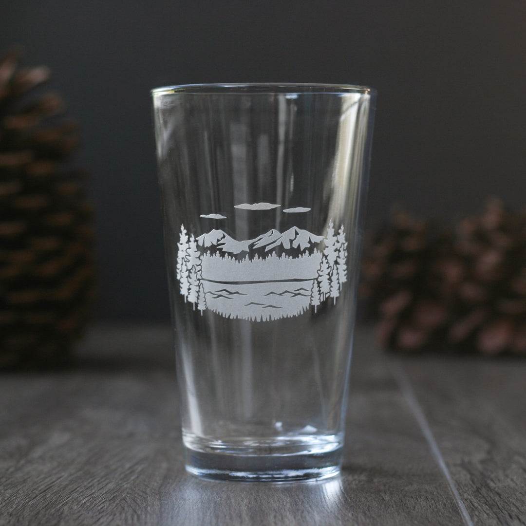 pint glass etched with a scene of the Three Sisters mountains with trees and a lake in the foreground