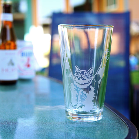Stretching Yoga Cat etched pint glass on an outdoor backyard patio table
