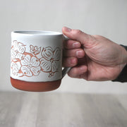 Hand holding a White + Red Clay Dogwood Flowers engraved mug