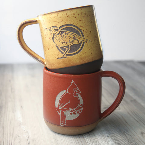 Handmade pottery mugs engraved with birds: yellow Western Meadowlark and red Cardinal.