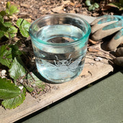 honey bee recycled glass tumbler full of water on the edge of a strawberry garden