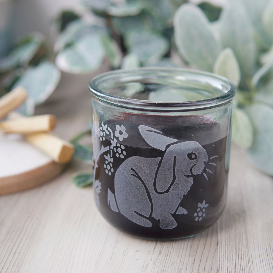 cute rabbits and blackberry branches engraved onto a short glass with red wine