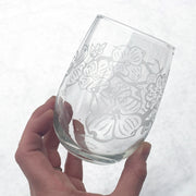dogwood flower branches engraved stemless wine glass in front of snow