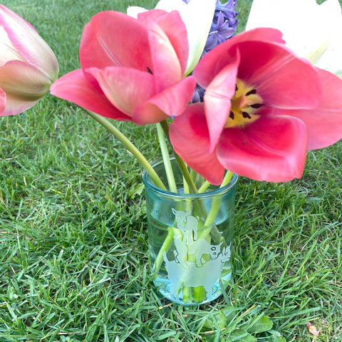 goat yoga recycled glass vase with tulips and hyacinth flowers in the grass